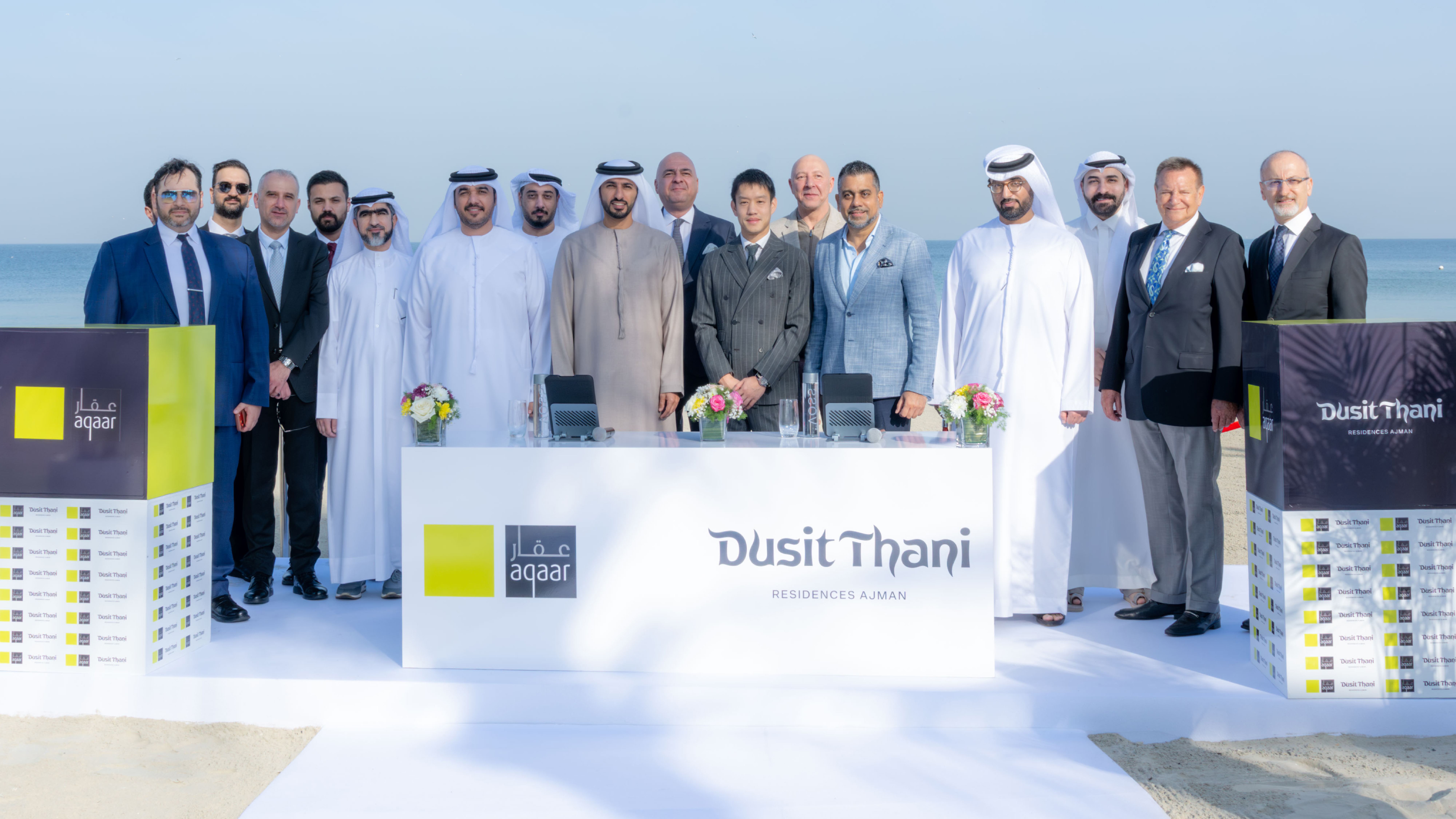 Officials signing partnership documents at a beachfront event for Aqaar and Dusit Thani Residences Ajman.