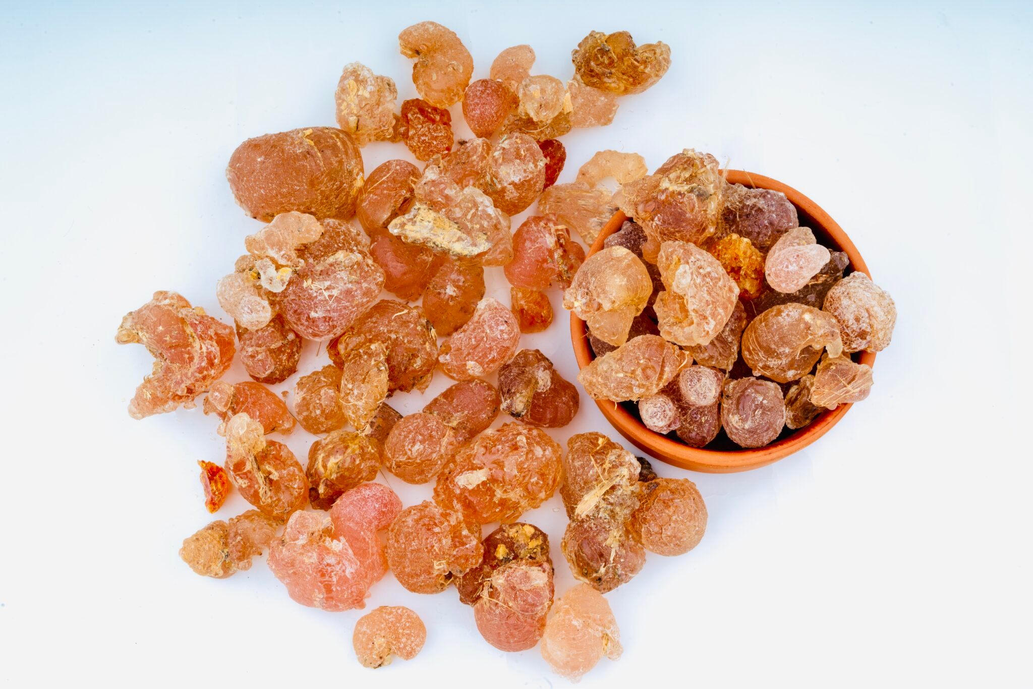 Gum arabic resin pieces in a bowl and scattered – natural arabic gum.