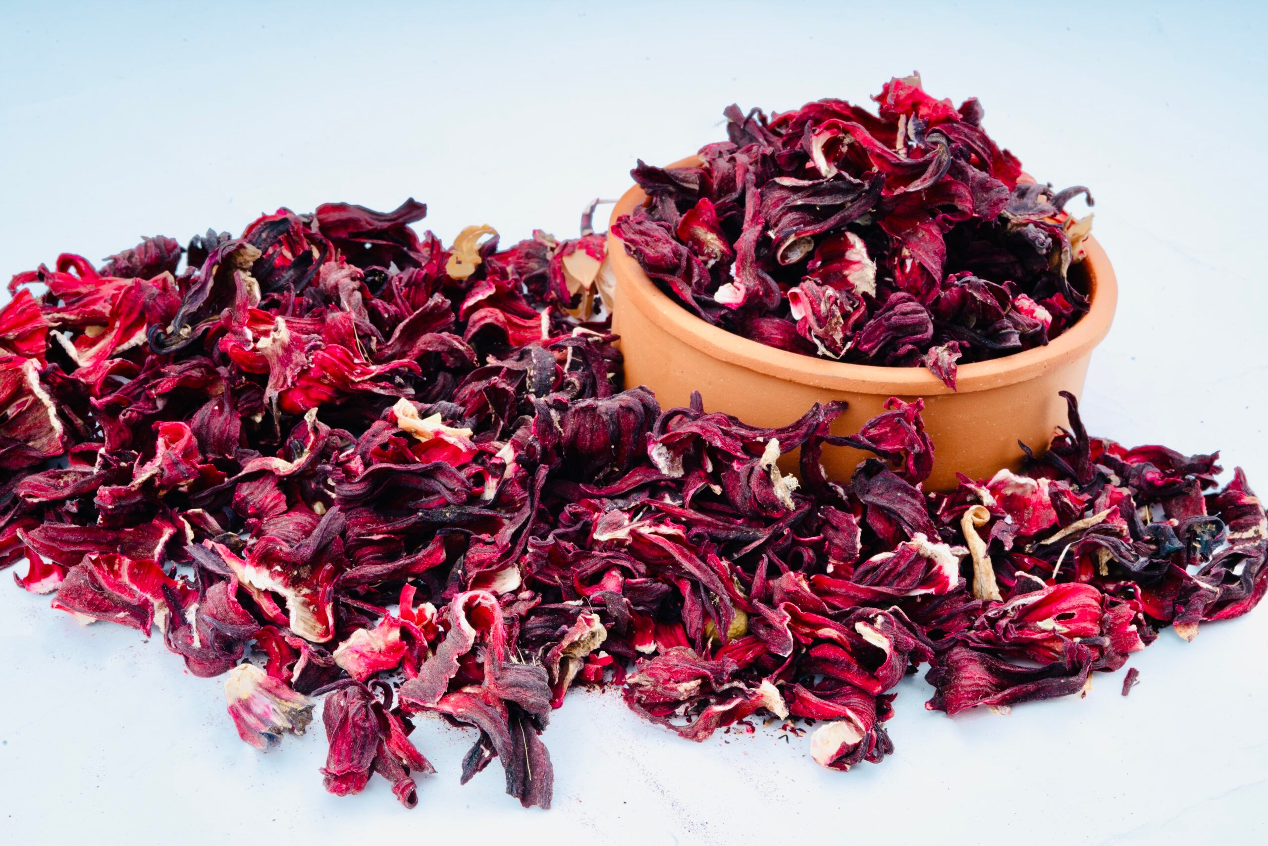 Dried hibiscus flowers in a bowl and scattered – natural herbal ingredient.
